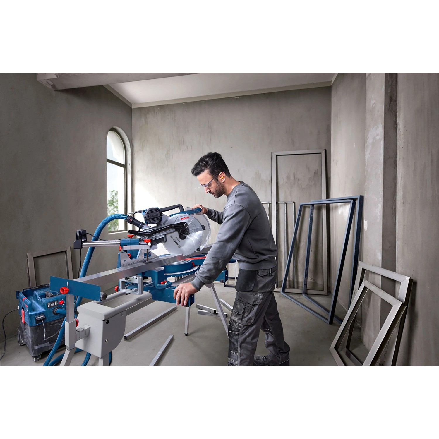 Mann bedient Bosch Professional Kapp- und Gehrungssäge GCM 340-305 D. Blaue Säge mit Verlängerungen für präzise Holzarbeiten.