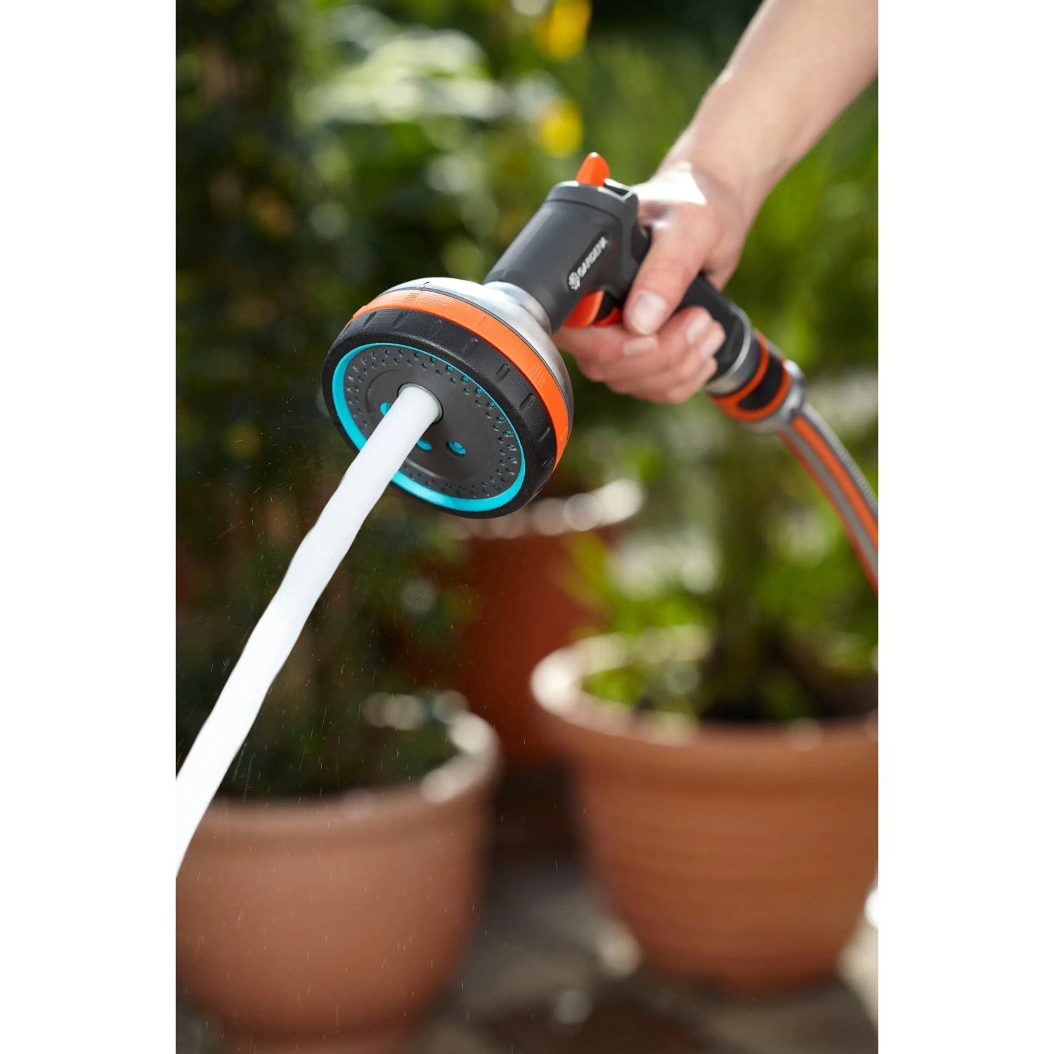 Gardena Premium Multibrause in Aktion: Hand hält Gartenspritze mit Wasserstrahl. Ideal für Gartenbewässerung.