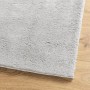 Grauer, weicher Kurzflor-Teppich aus Polyester mit flauschiger Oberfläche auf Holzfußboden. Waschbar.