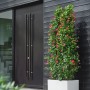 Weißer Elho Blumentopf Vivo Next Lang (59cm) mit Rollen und roter Pflanze vor dunkler Hauswand.