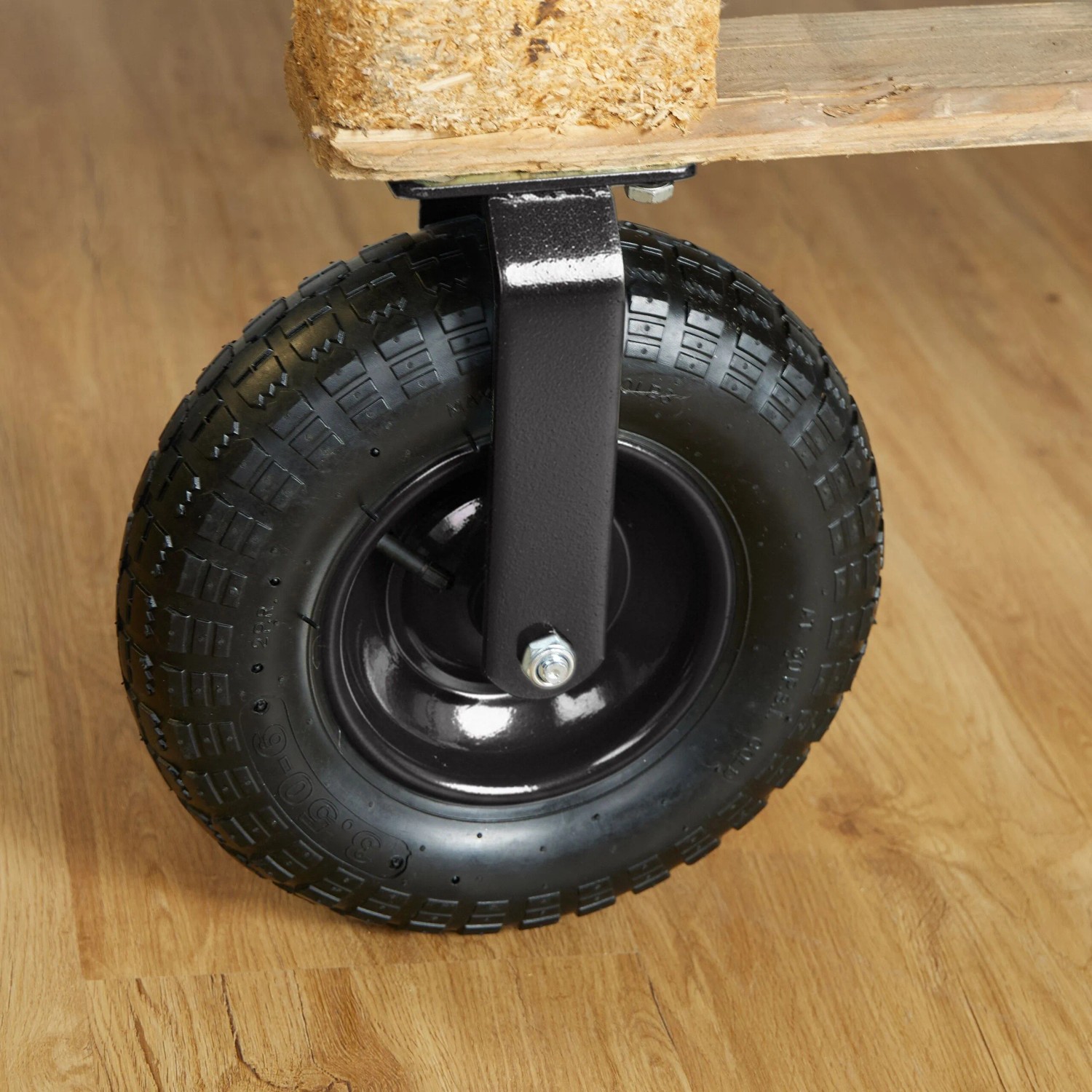 Schwarze luftbereifte Schwerlast-Bockrolle aus Gummi und Stahl, an Holzpalette montiert. Für Lasten bis 120 kg.