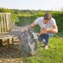 Mann reinigt Gardena smart Sileno life Mähroboter mit Wasserschlauch im Garten.