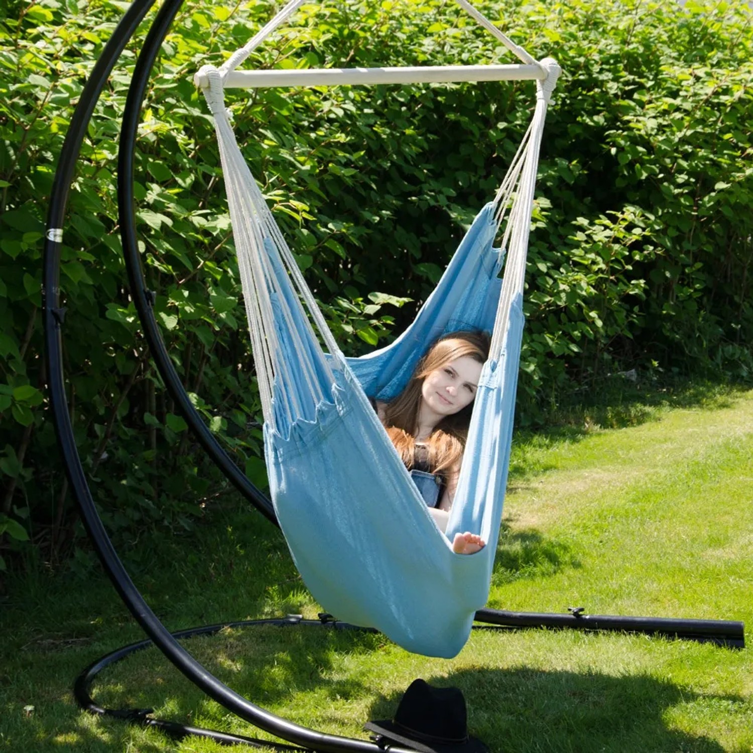 AMANKA Hängesessel Pazifik-Blau mit Person im Garten. Bequemer Schwebesessel bis 150kg.