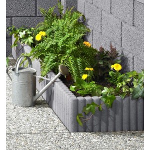 Grauer Rundpalisaden-Randstein (50 cm) als Beeteinfassung mit Pflanzen und Gießkanne.