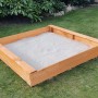 Quadratischer Promadino Sandkasten aus Kiefernholz, gefüllt mit Sand, im Garten.