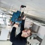 Mann bohrt mit blauem Bosch Professional Akku-Bohrhammer in Betondecke. Trägt Schutzbrille und Gehörschutz.