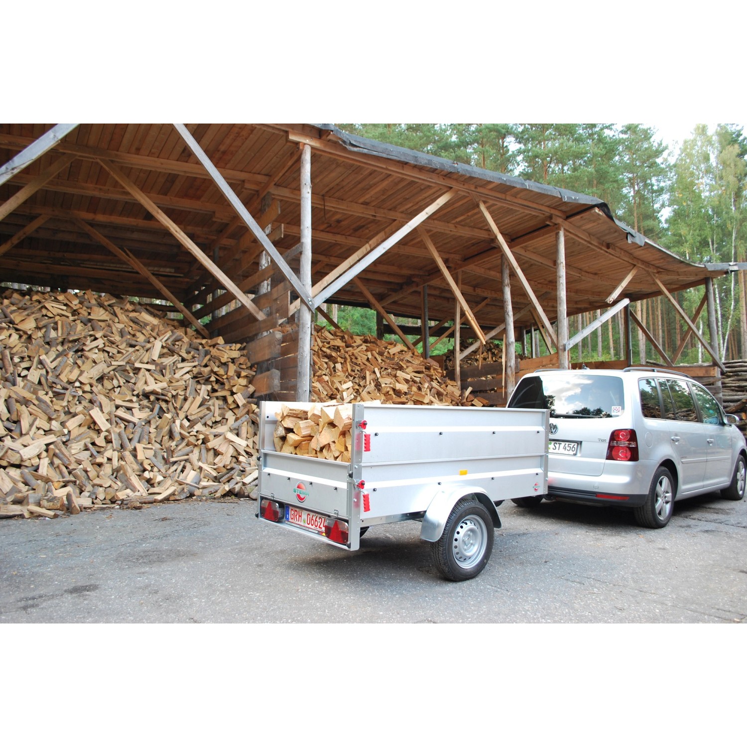 Stema Anhänger Basic 750 mit Stützrad, Bordwandaufsatz und Flachplane lichtgrau beladen mit Holz.