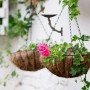Weiße Relaxdays Vogeltränke aus Gusseisen mit Blumenmuster und zwei bepflanzten Hängekörben.