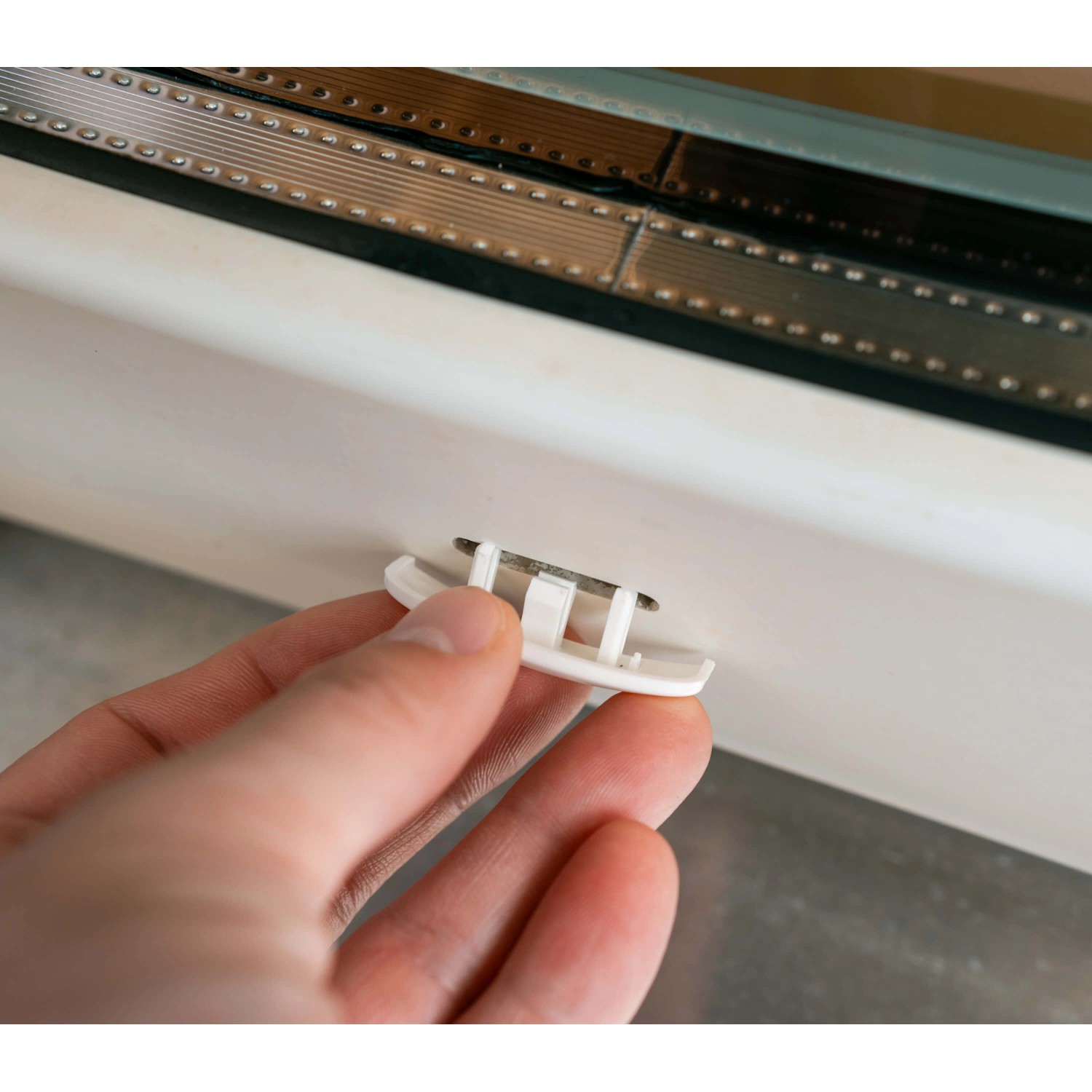 Bauheld Wasserschlitzkappe (RAL 9003) wird in ein Fenster eingesetzt.