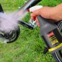 Hand sprüht Ballistol Fahrrad-Reiniger 750 ml auf Fahrradkette. Graue Flasche reinigt Fahrrad im Gras.