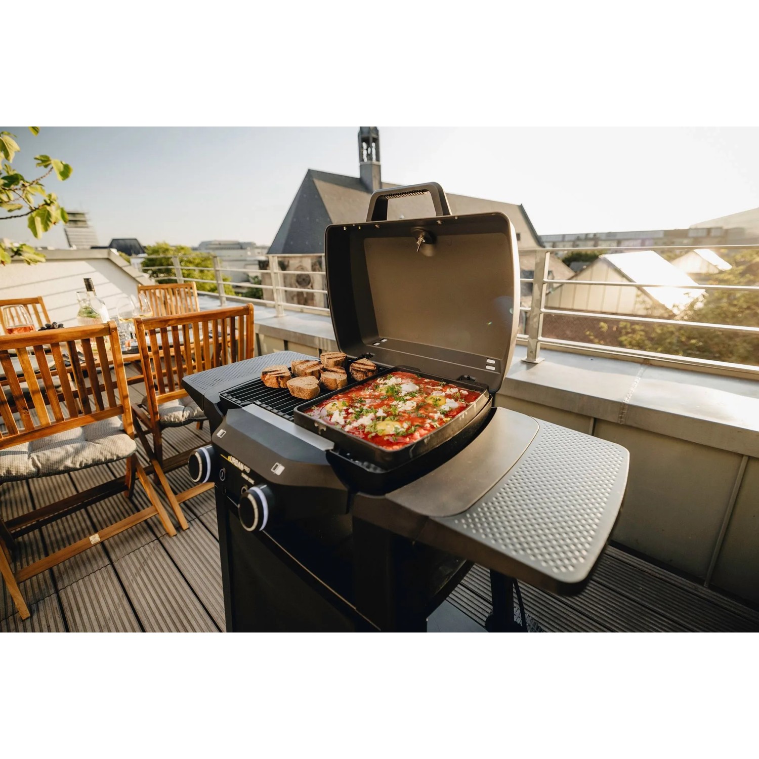 Enders Elektrogrill eUrban Pro 2 Turbo mit Trolley auf Balkon mit Grillgut und Pizza.