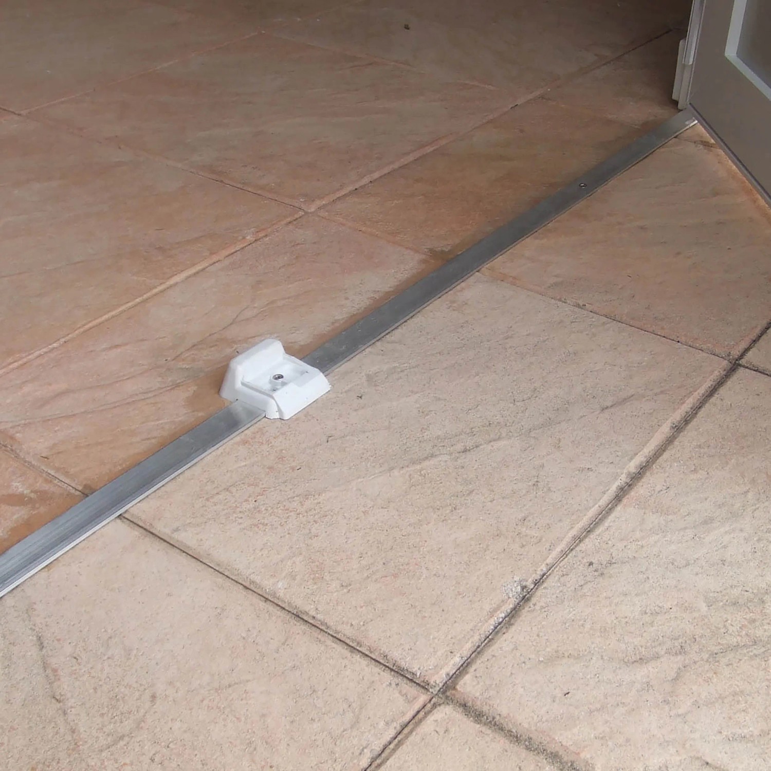 Detailaufnahme einer Bodenschiene für ein Grosfillex Gartenhaus auf Fliesen.