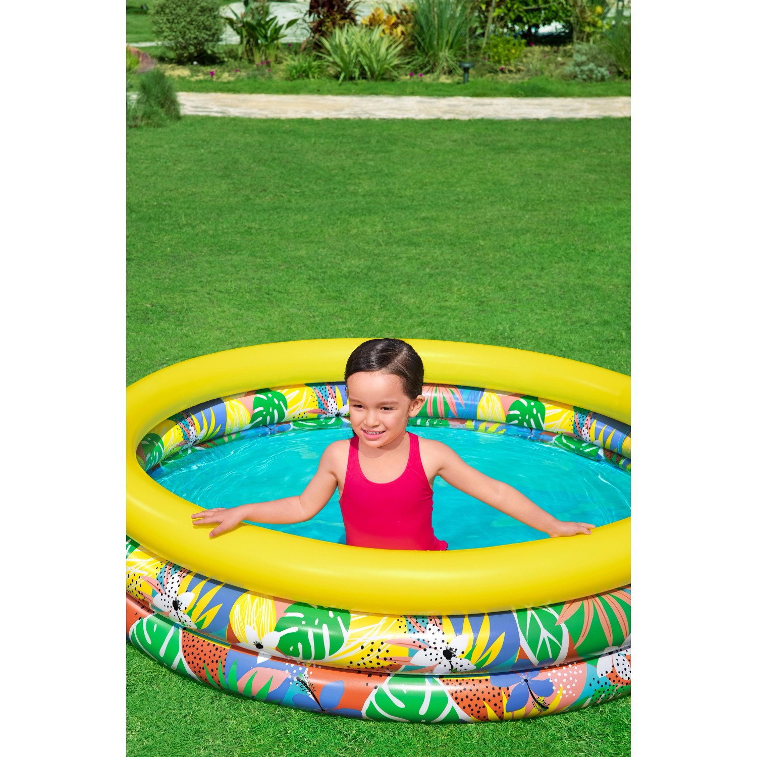 Bestway Planschbecken Floral Paradise mit Kind im Garten. Rundes Becken mit bunten Mustern und gelbem Rand.