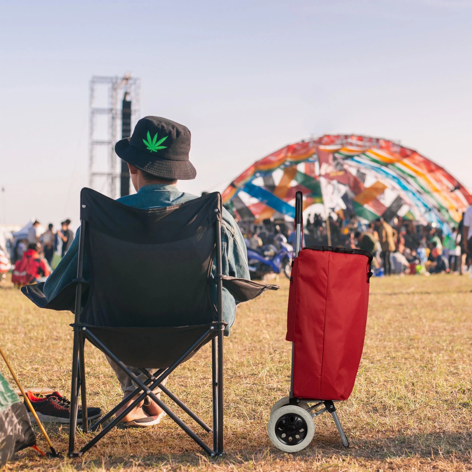 Roter Relaxdays Einkaufstrolley aus Stoff und Stahl neben Person auf Festival. Faltbarer Trolley mit 2 Rädern.