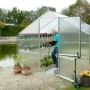 KGT Gewächshaus Orchidee Alu blank, 12,74 m², mit offener Tür und Person beim Gießen von Pflanzen.