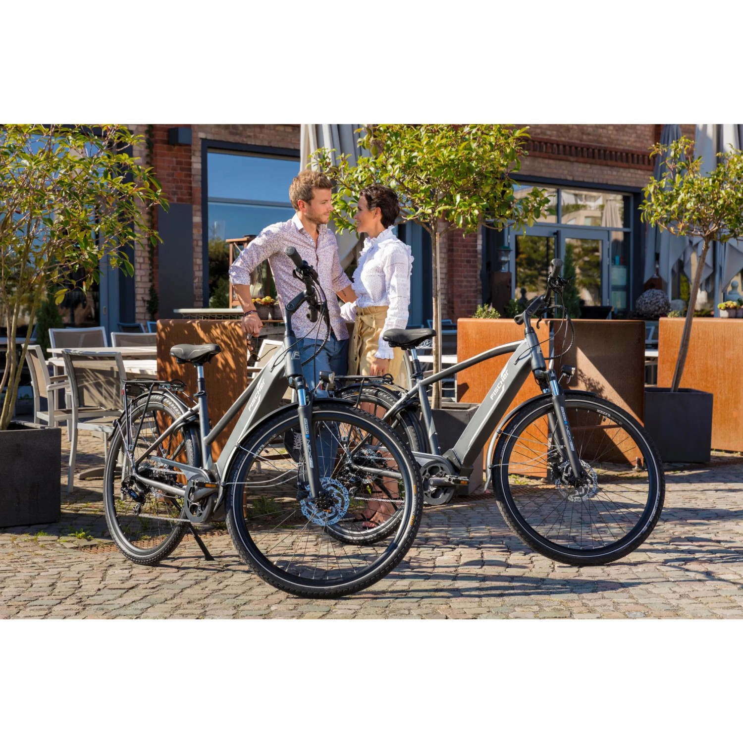Zwei graue Fischer E-Bikes Viator 5.0i vor einem Gebäude. E-Bike mit Diamantrahmen und Mittelmotor.