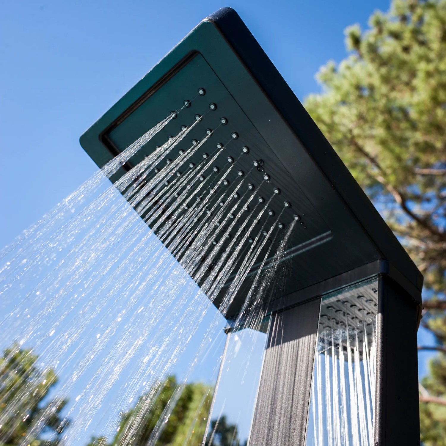 Gre Aluminium-Solardusche Luxe 38 l mit laufendem Wasser vor blauem Himmel und Baum.