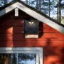 Schwarzes Fledermaushaus aus Zedernholz für bis zu 75 Fledermäuse am roten Haus.
