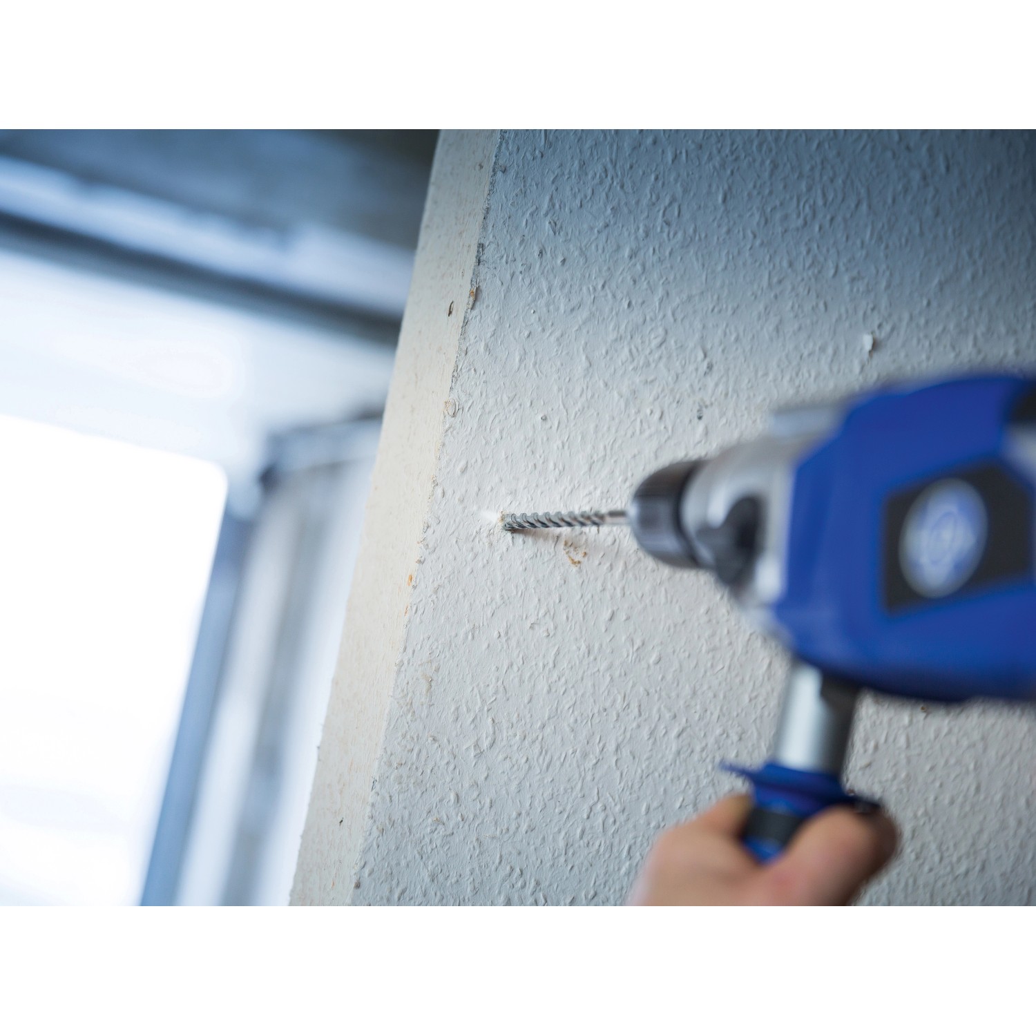 Mauerdurchbruch mit LUX Classic Betonbohrer 8 mm. Bohrer im Einsatz an weißer Wand.