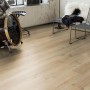 Verlegtes Laminat LAM.PROG. WR Eiche WATERFORD in Wohnraum-Szene mit Schlagzeug und Stuhl.
