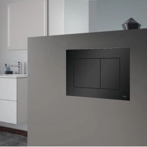 Schwarze WC-Betätigungsplatte mit zwei Tasten, in grauer Wand montiert. Modernes Design für KOLMAN WC-Komplettset im Bad.