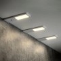Drei flache SOTECH GIULIA II LED-Unterbauleuchten, silbergrau, warmweiß leuchtend, eine mit Sensor.