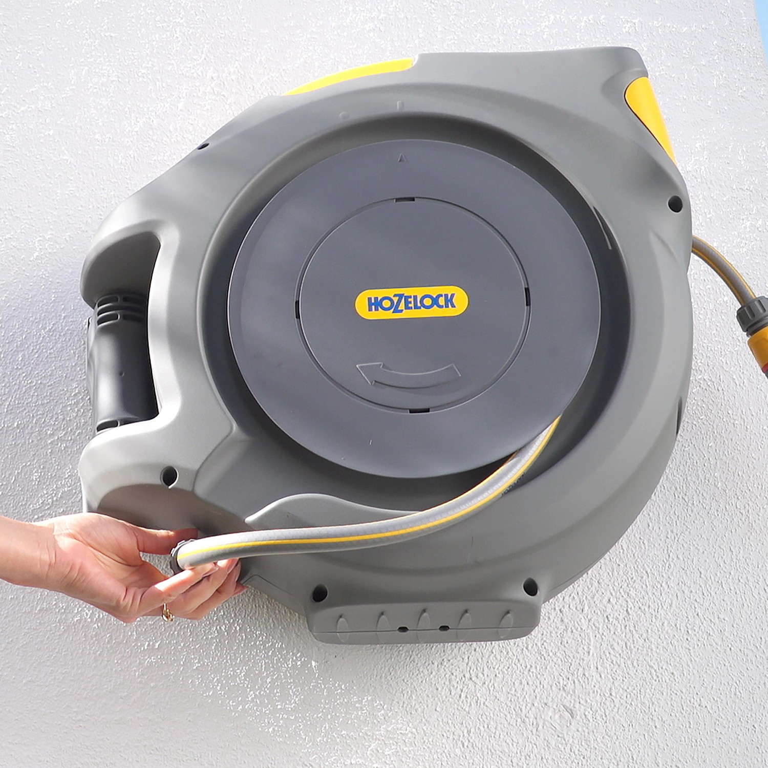 Hozelock Auto Reel Schlauchtrommel mit 30m Schlauch, grau/gelb, an Wand montiert.