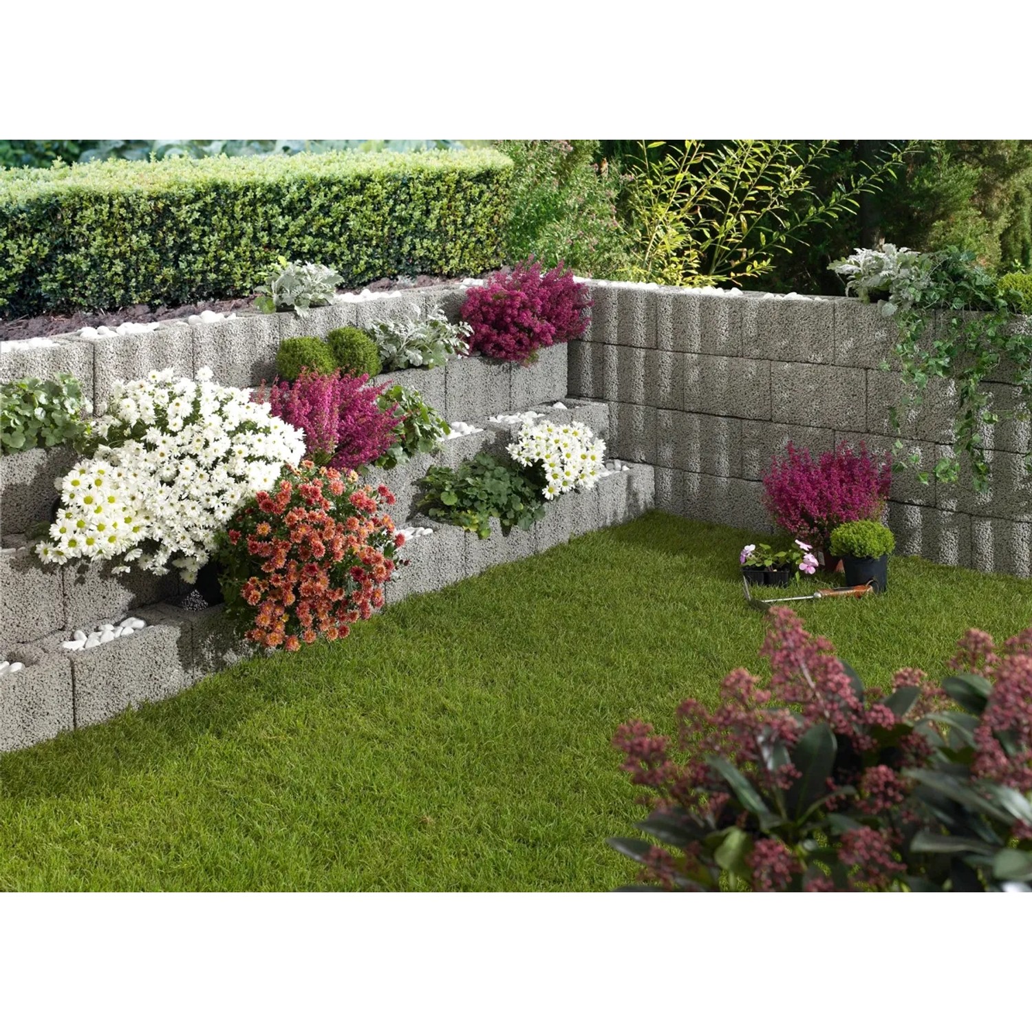 Bepflanzte graue Wellino Pflanzsteine als stufenförmige Hangbefestigung im Garten.