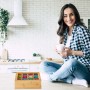 Relaxdays Bambus Teebox Natur mit 12 Fächern und Sichtfenster, gefüllt mit Teebeuteln, auf Küchenzeile. Lachende Frau.