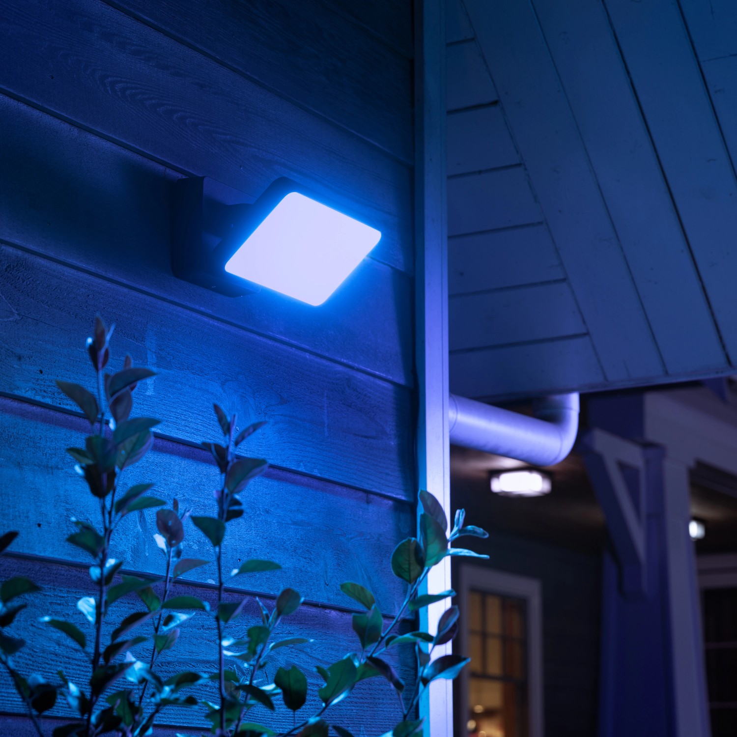 Philips Hue Discover LED-Wandleuchte mit blauem Lichtschein an Hauswand.