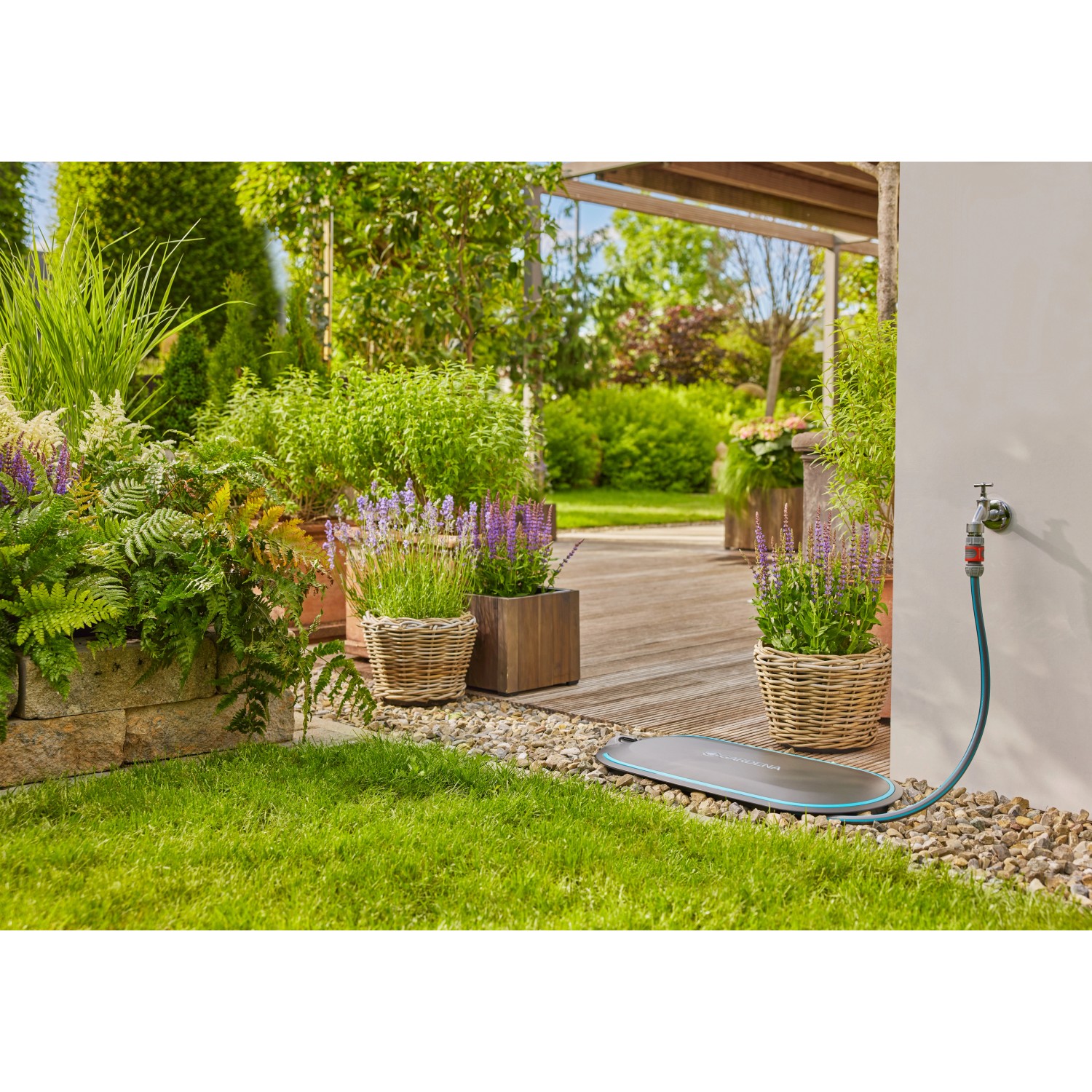 Gardena Undercover Schlauchbox RollUp M im Garten mit Schlauch am Wasserhahn.