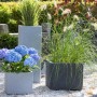 Scheurich Plaza High Pflanzsäule, 72,5 cm, Schwarz Granit, mit Pflanzen im Garten.