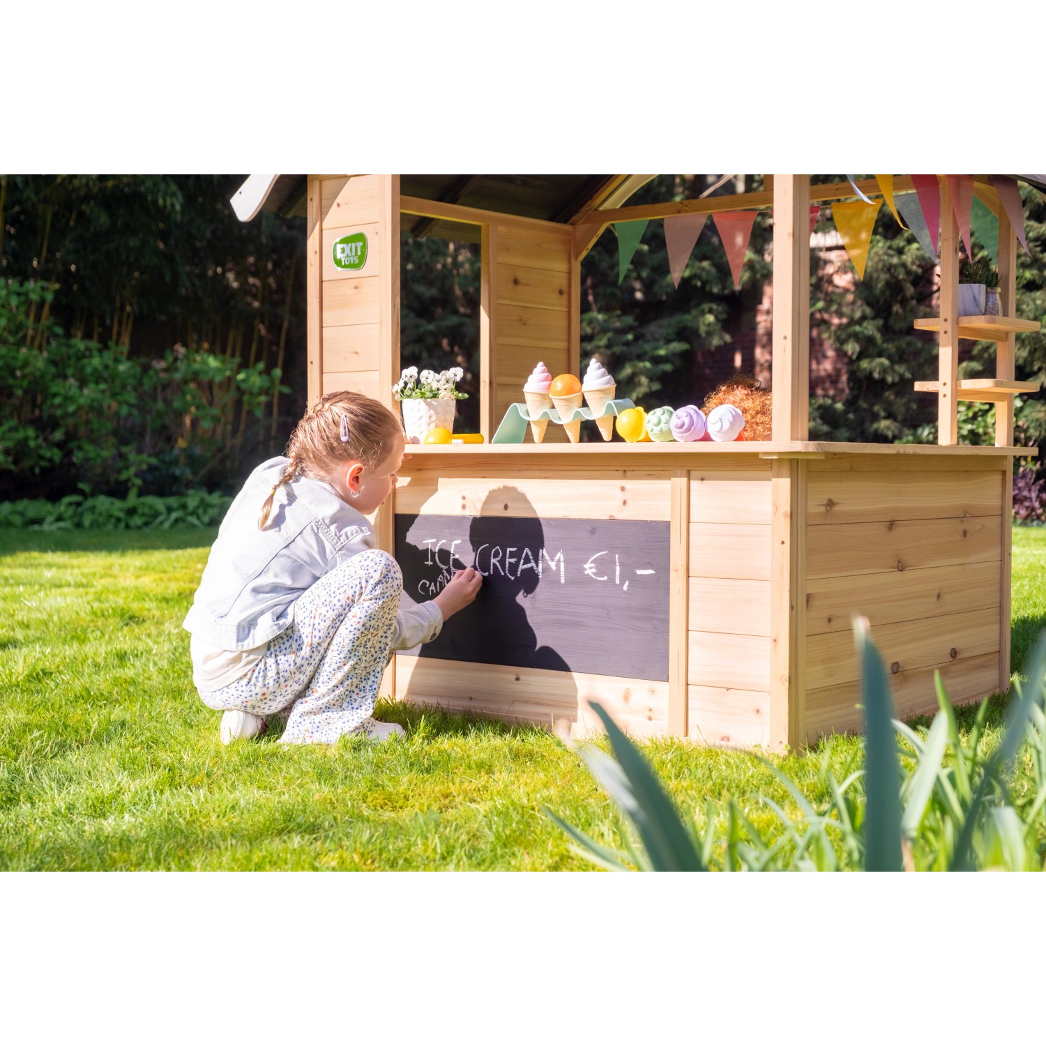 Exit Holzspielhaus Hika mit Kreidetafel und Mädchen beim Malen im Garten.