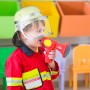 Kind mit gelbem Feuerwehrhelm (Relaxdays) mit Visier und rotem Megafon.