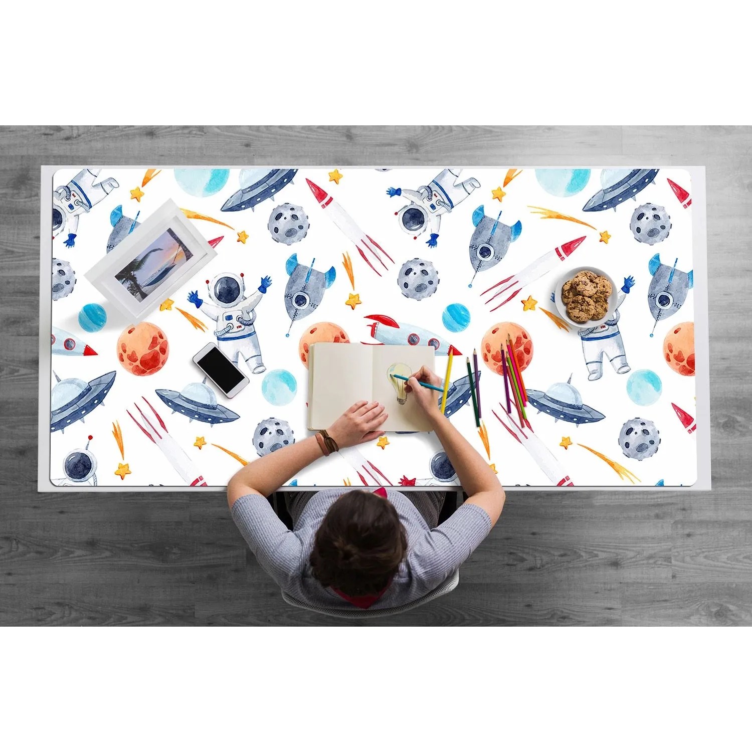 Mehrfarbige Tulup Schreibtischunterlage Astronaut 120x60 cm auf Schreibtisch mit Person.