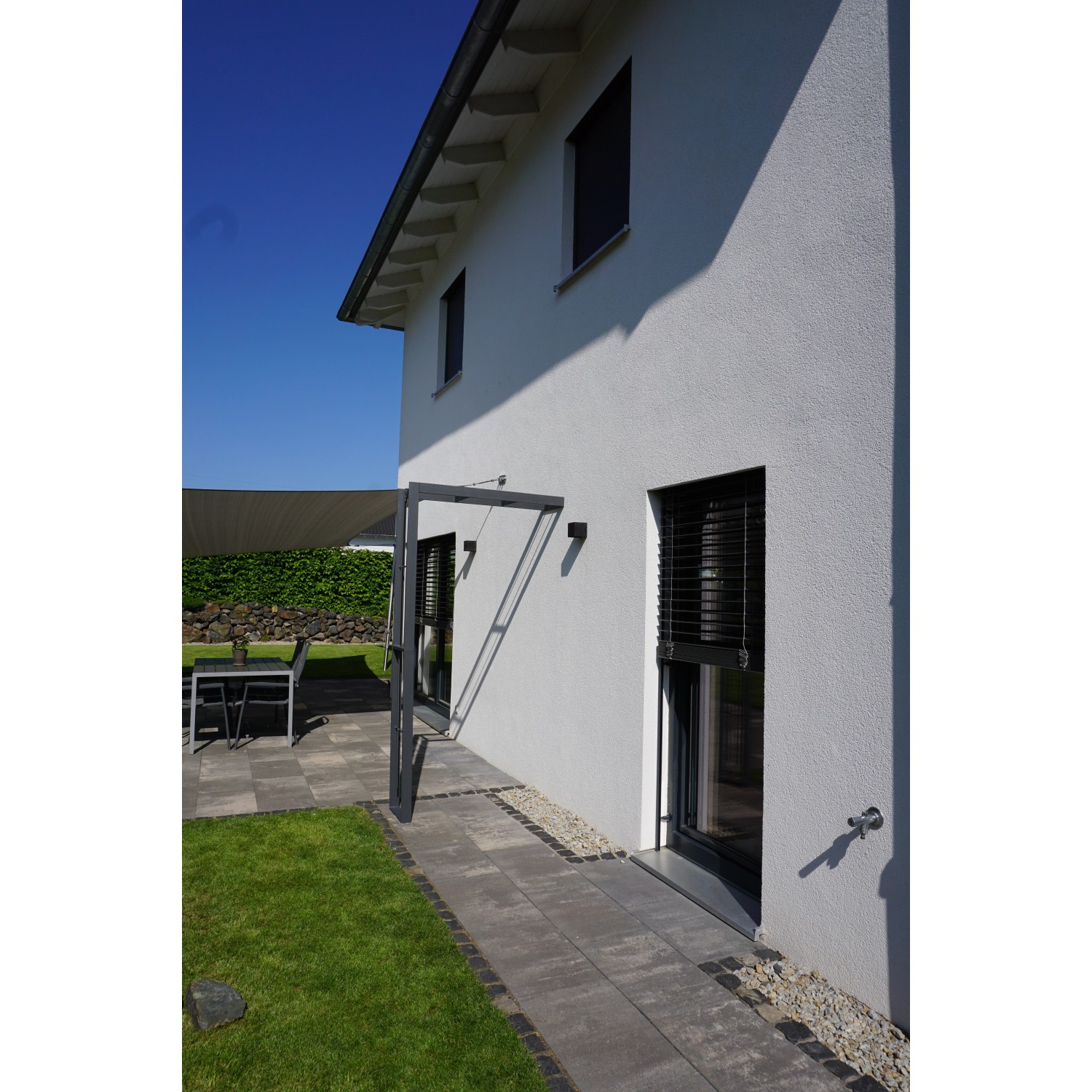 Eleo Rosenbogen Savona, anthrazit pulverbeschichtet, als Gartendeko an Hauswand montiert.