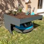 Anthrazitfarbene Mähroboter-Garage G60 mit Pflanzkasten und Mähroboter im Garten.
