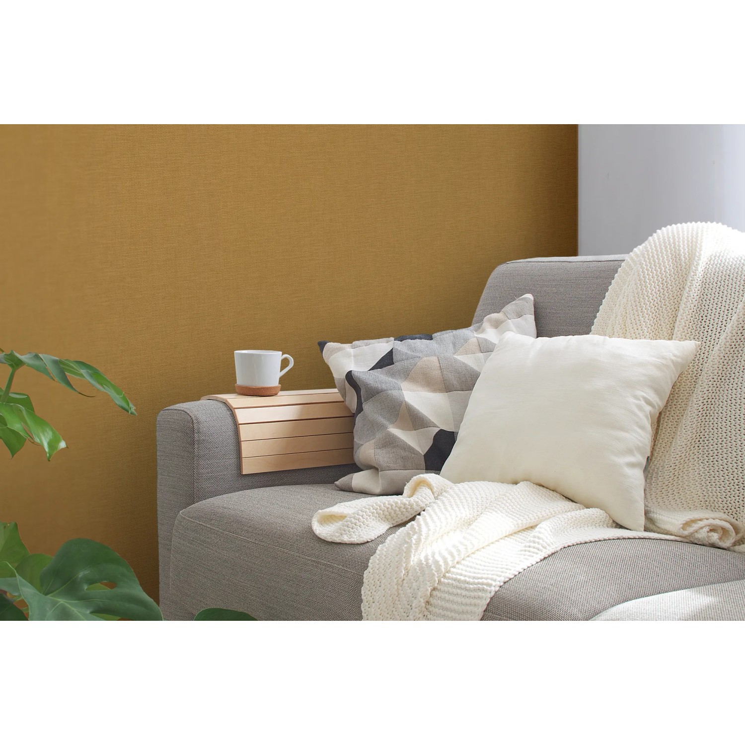 Strukturierte, matte, gelbe Vliestapete Uni von OBI an Wohnzimmerwand hinter Couch.