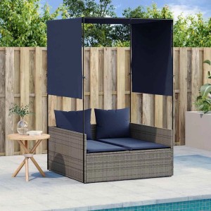 Graue Poly-Rattan Doppel-Sonnenliege mit marineblauen Kissen, Dach und Vorhängen am Pool. Gartenmöbel.