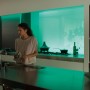 Frau in Küche mit Philips Hue Lightstrip Plus, der grünes Licht ausstrahlt.