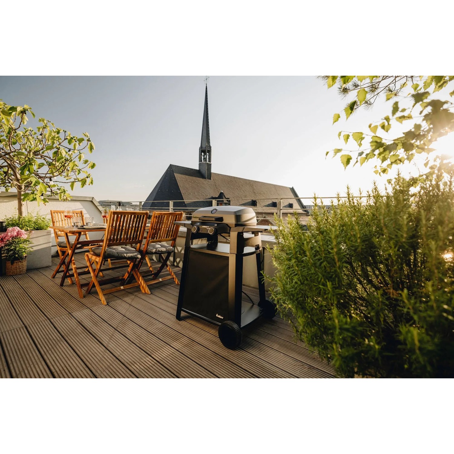 Enders Elektrogrill eUrban Pro 2 Turbo mit Trolley auf einer Dachterrasse mit Sitzgruppe.