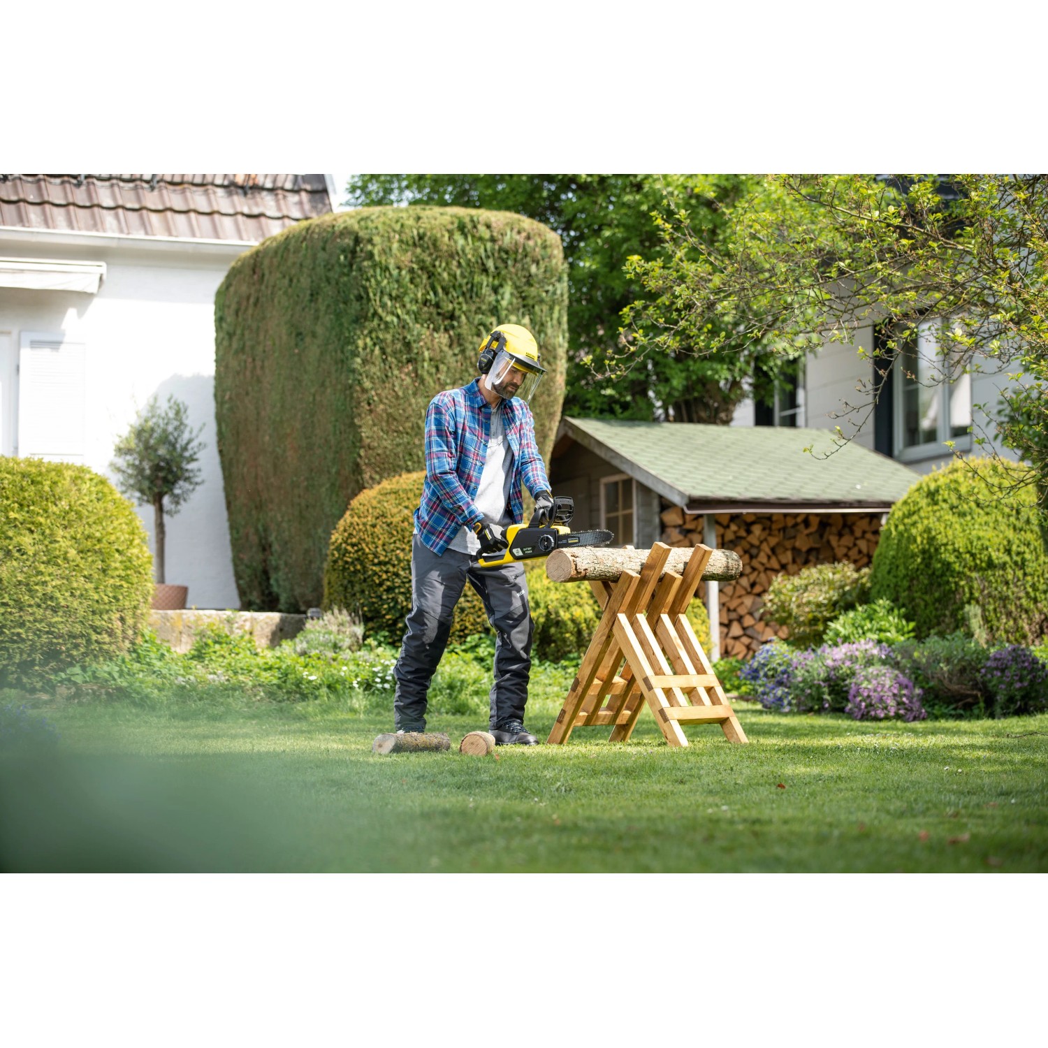 Mann sägt Holz mit der Kärcher Akku-Kettensäge CNS 18-30 im Garten.