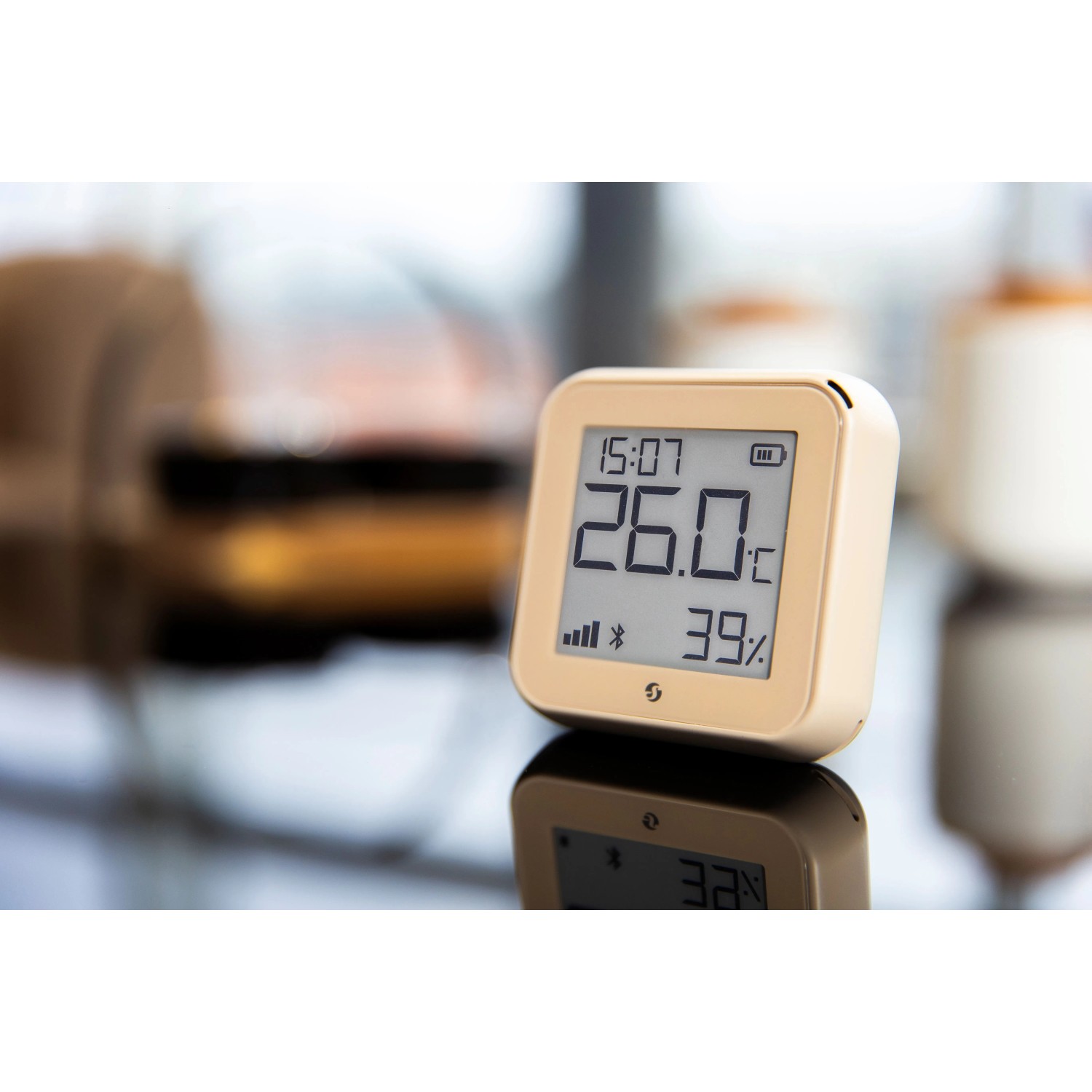 Beiger Shelly Temperatursensor Plus H&T G3 mit digitaler Anzeige von Temperatur und Luftfeuchtigkeit.