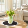 Rundes Tischset aus geflochtenem Seegras in Schwarz und Creme auf Holztisch mit Blumenvase.