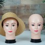 Zwei weibliche Mannequin-Köpfe, geschminkt, einer mit Strohhut, für Perücken- und Accessoire-Präsentationen.