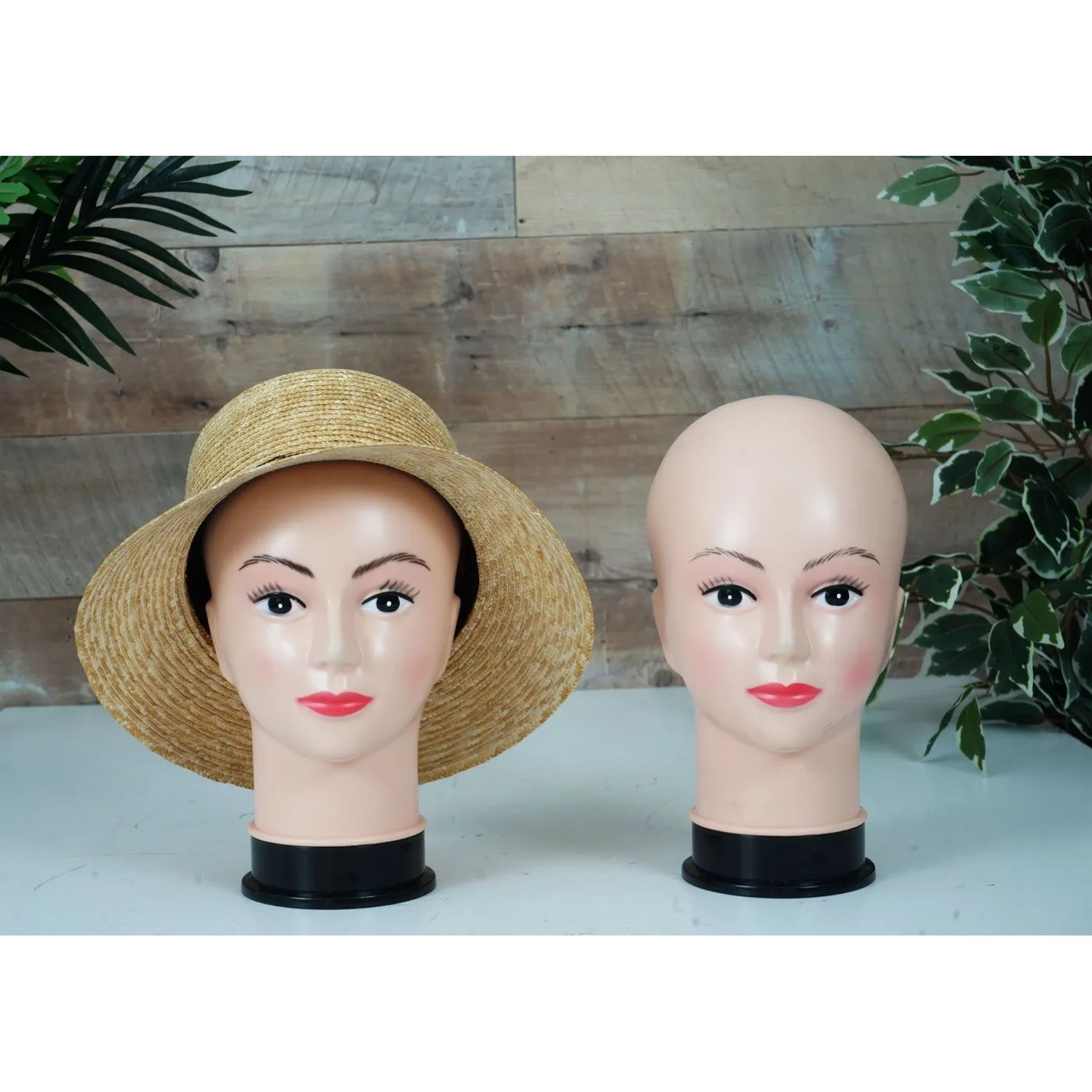 Zwei weibliche Mannequin-Köpfe, geschminkt, einer mit Strohhut, für Perücken- und Accessoire-Präsentationen.