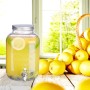 Klarer Glas-Getränkespender mit Zapfhahn, gefüllt mit Zitronenlimonade, auf Holztisch. Ideal für Gartenpartys.