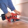 Black+Decker Bandschleifer KA86 beim Schleifen einer Sockelleiste. Rotes Gehäuse, Staubfangsack.