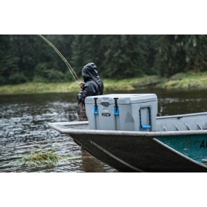 Dunkelgraue Kühlbox aus Kunststoff auf einem Boot, mit Angler im Hintergrund. Ideal für Outdoor-Aktivitäten.