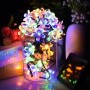 Bunte LED Solar-Lichterkette mit Kirschblüten in einem Glas, ideal für stimmungsvolle Weihnachtsbeleuchtung.